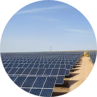 Solar panels installed in a green field under a clear blue sky.