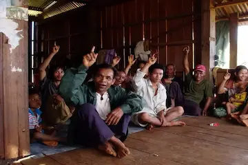 Group of people sat on the floor with their hands raised