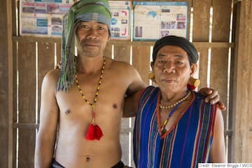 2 indigenous people standing together in hut