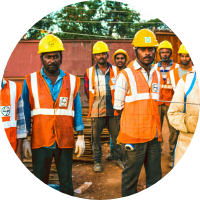 A group of men wearing orange vests and hard hats, standing together at a construction site.